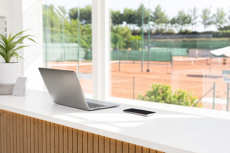 Postazione di segreteria con computer acceso, mouse e cuffie appoggiati sulla scrivania